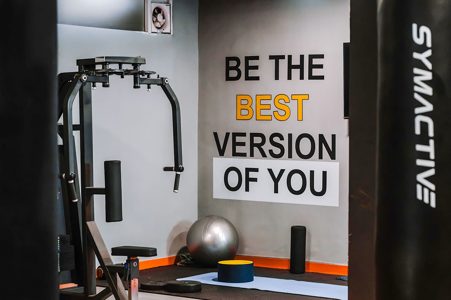 Gym corner with pec-deck machine and 'Be the best version of you' wall